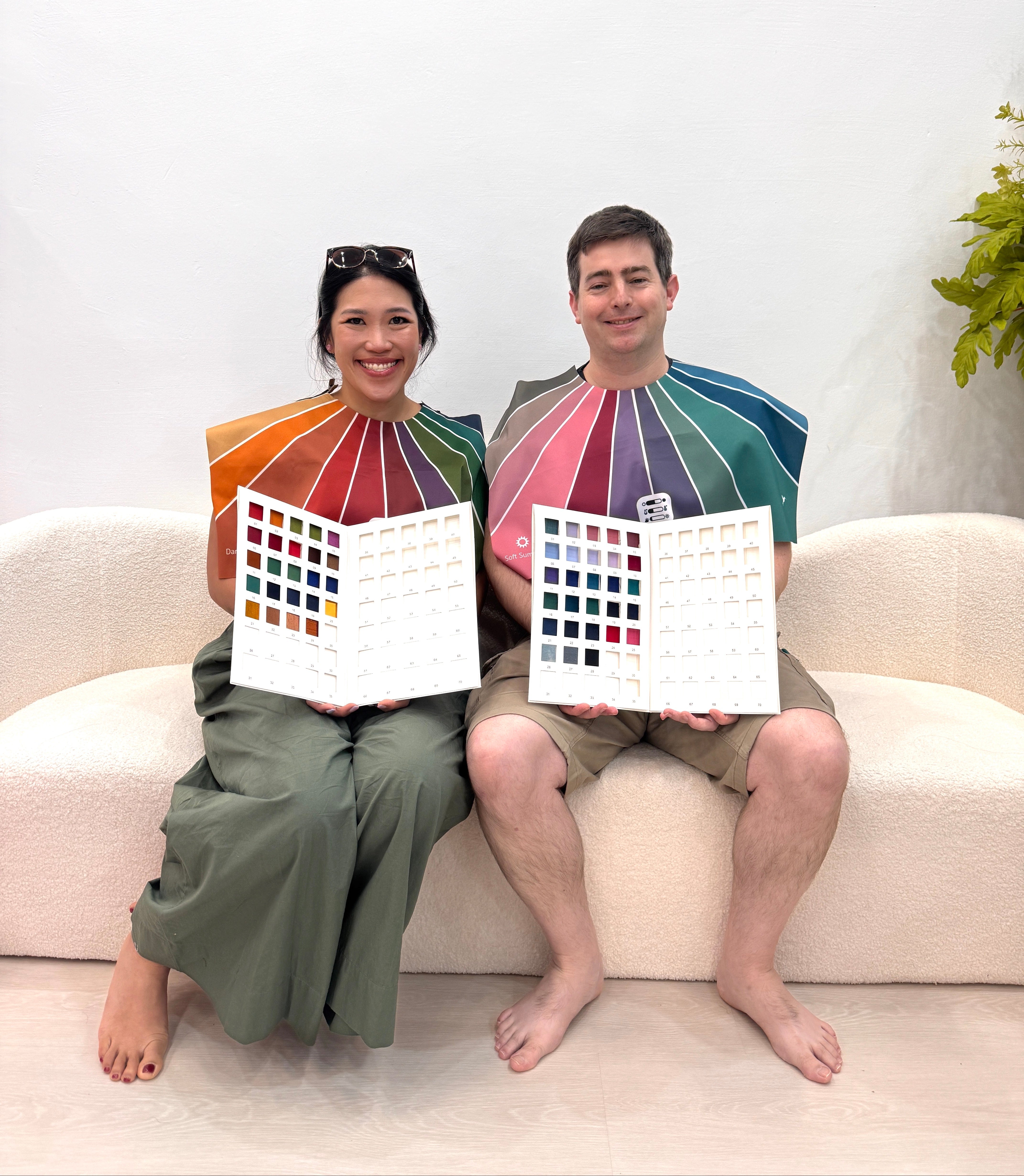 Two people sitting on a couch holding color swatch books.